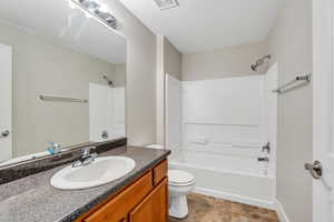 Full bath with toilet, shower / bath combination, vanity, and baseboards