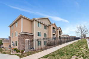View of side of home featuring stone siding, a fenced front yard, and stucco siding