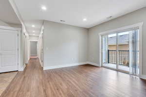 Unfurnished room with light wood finished floors, baseboards, and recessed lighting