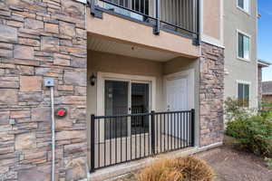 Entrance to property featuring stone siding, stucco siding, and a balcony