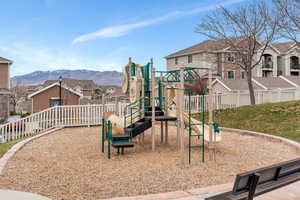 Community play area with fence, a mountain view, and a residential view