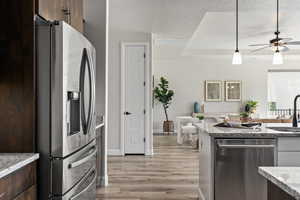Kitchen featuring stainless steel appliances, a sink, ceiling fan, light wood finished floors, and dark brown cabinets