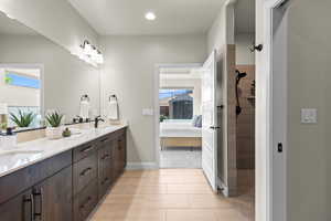 Ensuite bathroom featuring walk in shower, recessed lighting, double vanity, baseboards, and tile patterned flooring