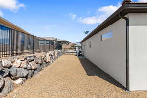 View of property exterior featuring fence, stucco siding, and a residential view