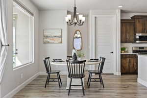 Dining room featuring a chandelier, light wood finished floors, baseboards, and recessed lighting