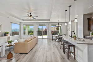 Living area featuring light wood-style floors, healthy amount of natural light, ceiling fan, a chandelier, and a textured ceiling