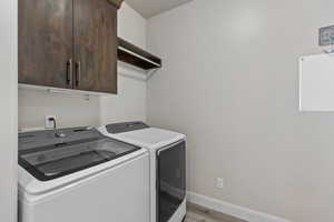 Washroom featuring independent washer and dryer, cabinet space, light wood finished floors, and baseboards