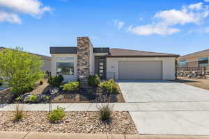 View of front of house featuring stucco siding, driveway, a garage, and fence