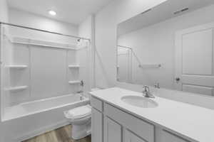 Bathroom featuring vanity, shower / bath combination, toilet, visible vents, and wood finished floors