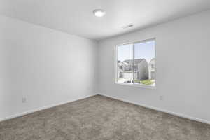 Empty room with baseboards, visible vents, and carpet