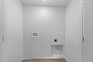 Clothes washing area featuring hookup for an electric dryer, washer hookup, baseboards, laundry area, and wood finished floors