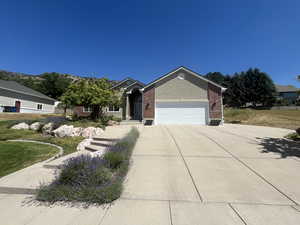 View of front of property with driveway, a garage, and brick siding