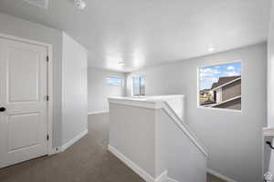 Hallway featuring an upstairs landing, baseboards, and dark carpet