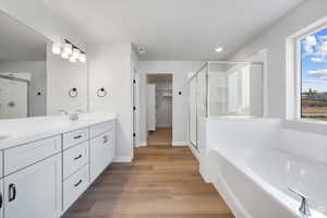 Full bathroom featuring double vanity, a sink, a stall shower, and wood finished floors