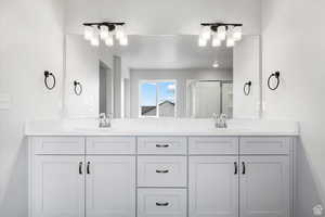 Full bath with double vanity, a sink, and a shower stall