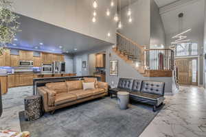 Living area with baseboards, marble finish floor, stairs, recessed lighting, and a high ceiling