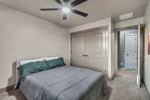 Bedroom featuring a closet, visible vents, baseboards, a ceiling fan, and carpet floors