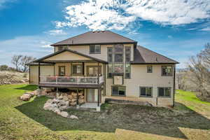 Back of house featuring a lawn, a shingled roof, and a deck
