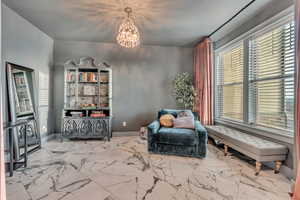 Living area with marble finish floor, baseboards, and an inviting chandelier
