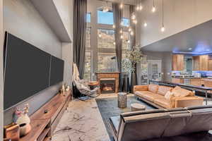 Living area featuring marble finish floor, recessed lighting, a towering ceiling, and a glass covered fireplace