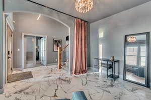 Entrance foyer featuring marble finish floor, arched walkways, and stairs