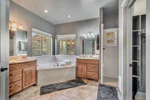 Bathroom with tile patterned flooring, recessed lighting, a garden tub, a notable chandelier, and two vanities