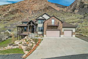 Craftsman-style home featuring a balcony, driveway, stone siding, an attached garage, and a mountain view