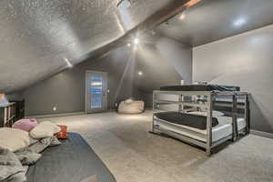 Bedroom with lofted ceiling, carpet, baseboards, access to outside, and a textured ceiling