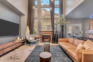 Living area featuring a high ceiling, marble finish floor, and a glass covered fireplace