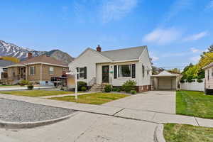 Bungalow-style home with an outbuilding, a mountain view, a detached garage, a chimney, and a front yard