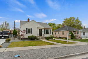 Bungalow-style house with roof with shingles, a gate, a chimney, fence, and a front yard
