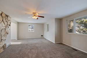 Unfurnished living room with carpet, baseboards, visible vents, and a ceiling fan