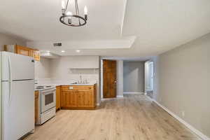 Kitchen featuring a textured ceiling, light countertops, light wood finished floors, white appliances, and a sink