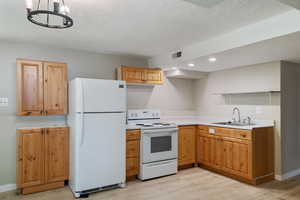 Kitchen with light countertops, visible vents, white appliances, a sink, and light wood-style floors
