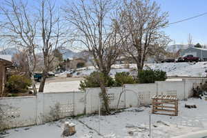 Yard layered in snow featuring a fenced front yard