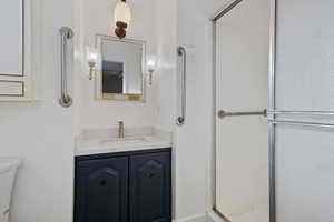 Bathroom featuring vanity, toilet, and a shower stall