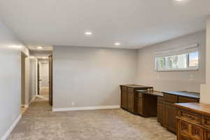 Kitchen featuring dark countertops, baseboards, light colored carpet, and recessed lighting