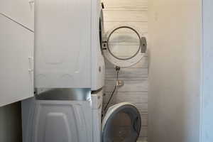 Washroom featuring stacked washer / dryer and laundry area
