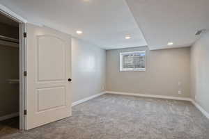 Below grade area with baseboards, visible vents, recessed lighting, and carpet