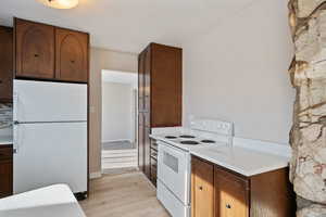 Kitchen featuring white appliances, light countertops, light wood-style flooring, and baseboards