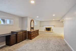 Interior space featuring baseboards, recessed lighting, a brick fireplace, and light carpet