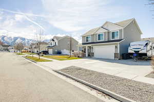 View of front facade with an attached garage, a residential view, driveway, a shingled roof, and a mountain view