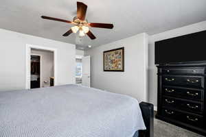 Bedroom featuring a closet, carpet floors, a spacious closet, a textured ceiling, and ceiling fan