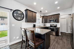 Kitchen with a sink, a peninsula, stainless steel appliances, visible vents, and dark brown cabinets