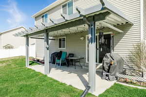Rear view of house with a pergola, a lawn, fence, and a patio