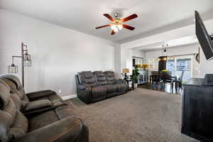 Carpeted living area with a ceiling fan and baseboards