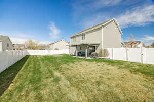 Rear view of property with a fenced backyard, a residential view, a gate, a yard, and a patio area