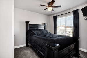 Bedroom with baseboards, ceiling fan, and dark carpet