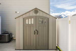 View of shed featuring central air condition unit, fence, and a mountain view