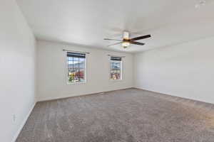Unfurnished room featuring carpet floors, a ceiling fan, and baseboards